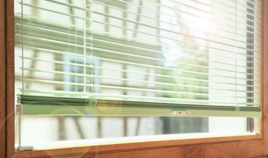 Elegantes Holzfenster mit Alu-Jalousien und Fachwerkhaus gegenüber