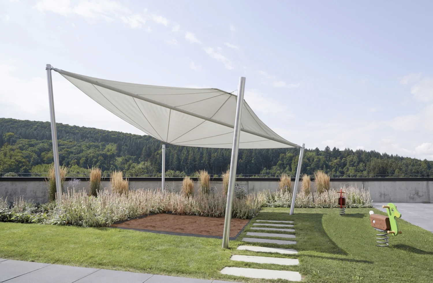 Moderne Sonnensegel auf einem Spielplatz mit grüner Landschaft im Hintergrund