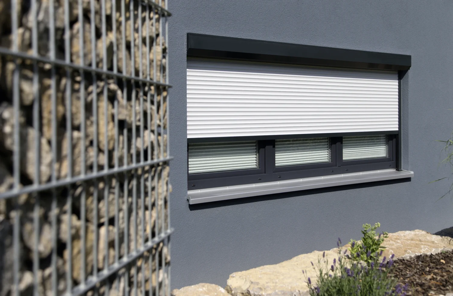 Moderne Hausfassade mit geschlossenen Rollläden und gepflegtem Steingarten