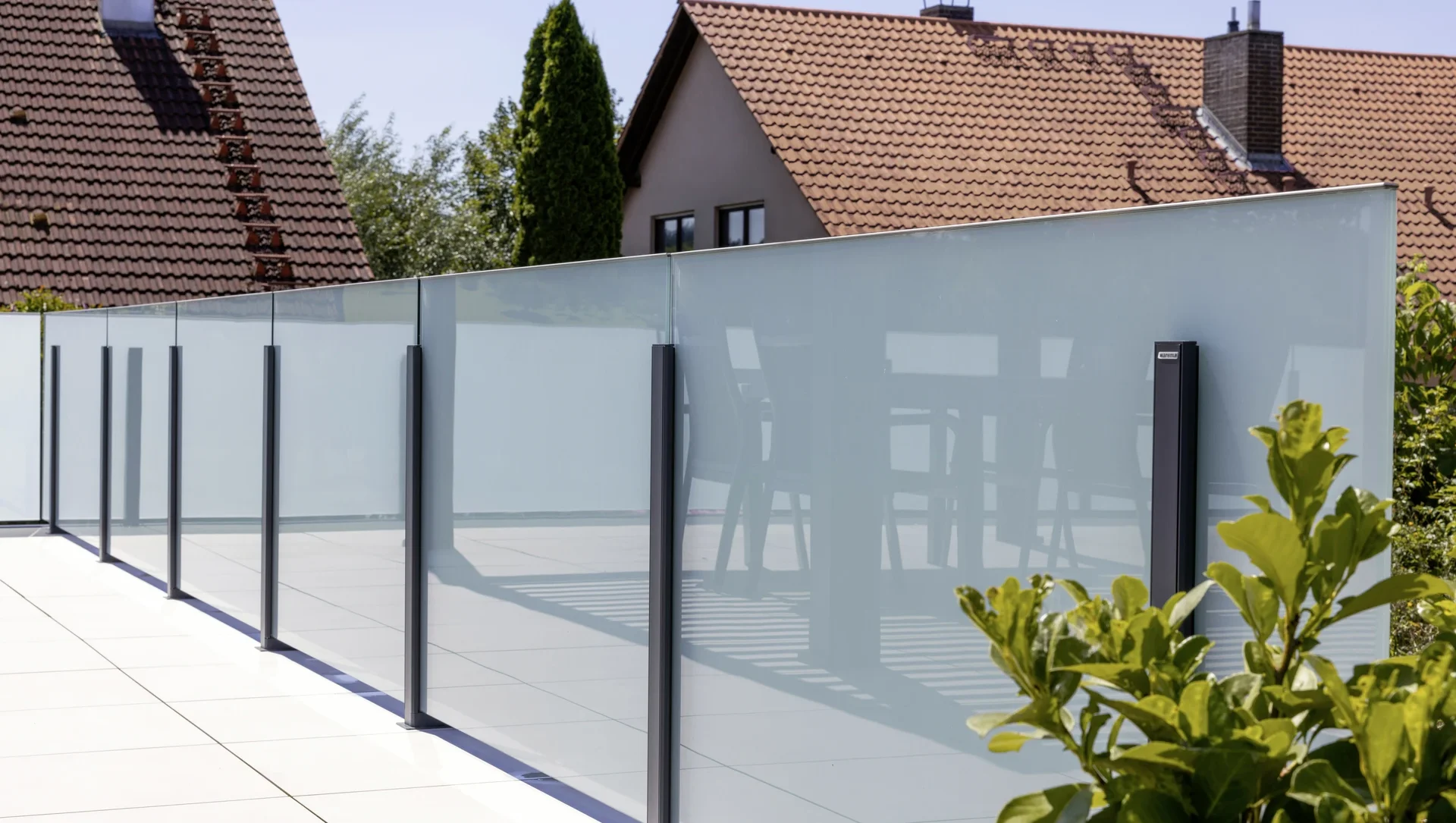 Moderne Glasabtrennung auf einer Terrasse mit Sichtschutz und Pflanzen