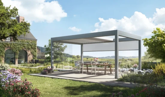 Moderne Pergola auf einer grünen Terrasse mit Blumengarten und Landhaus im Hintergrund